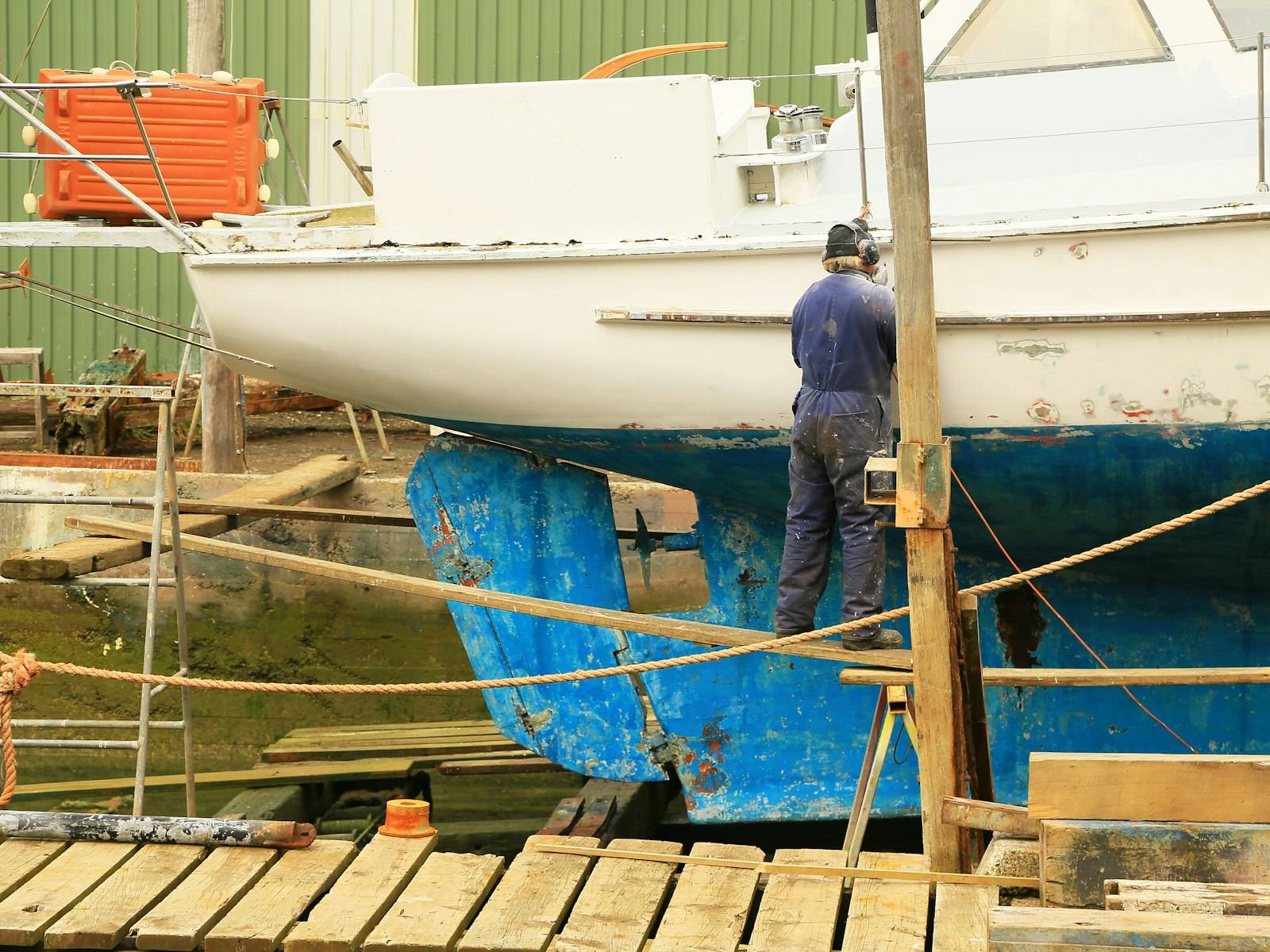 Technician in a boatyard dry dock working on the hull of a boat during a repair and maintenance project